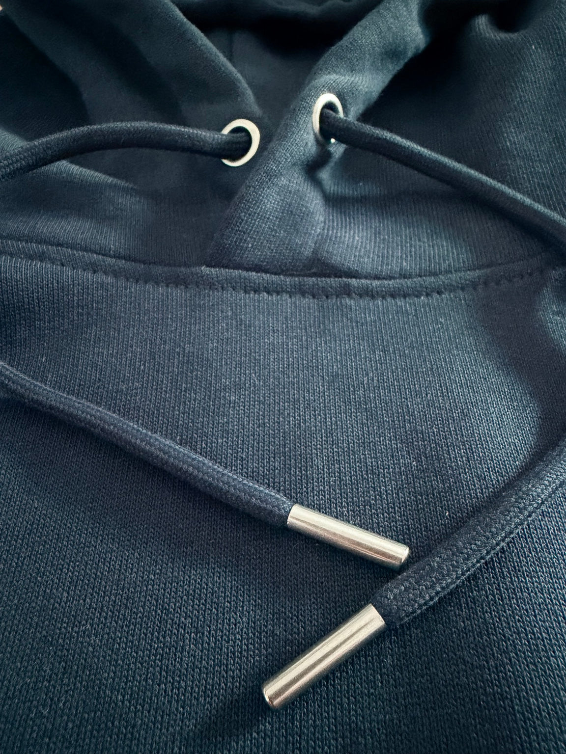 Detailaufnahme der Kapuze mit Metallösen, Kordeln und Metallenden am ALPENGRAT Organic Hoodie